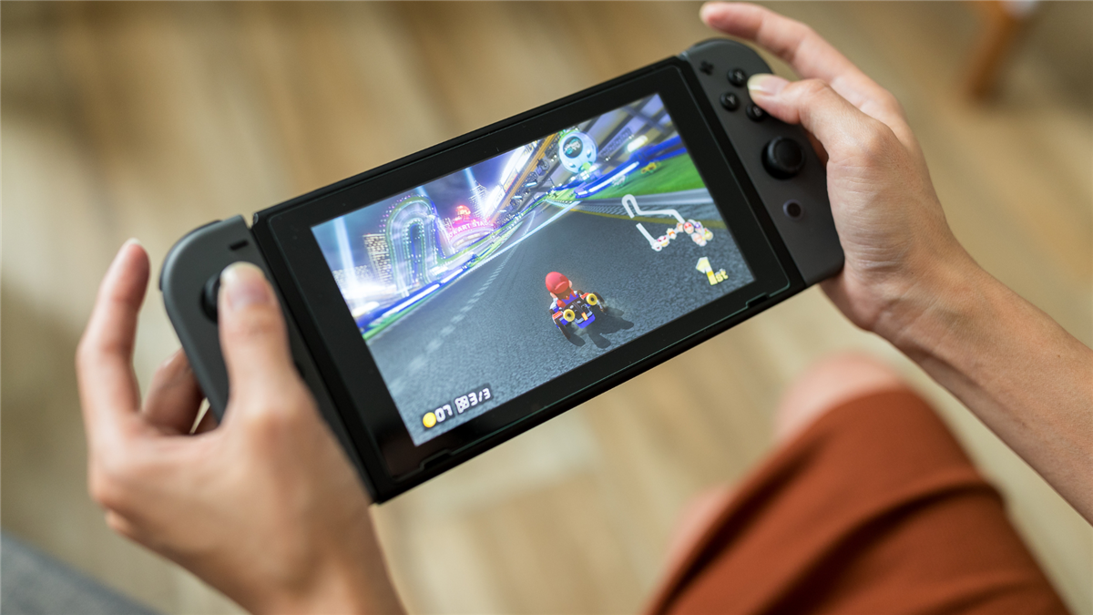 Person holder Nintendo Switch i hendene med Mario Kart på skjermen - Klikk for stort bilde