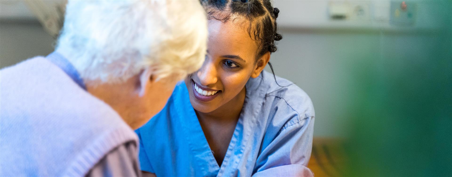 Helsearbeider som hjelper en gammel dame