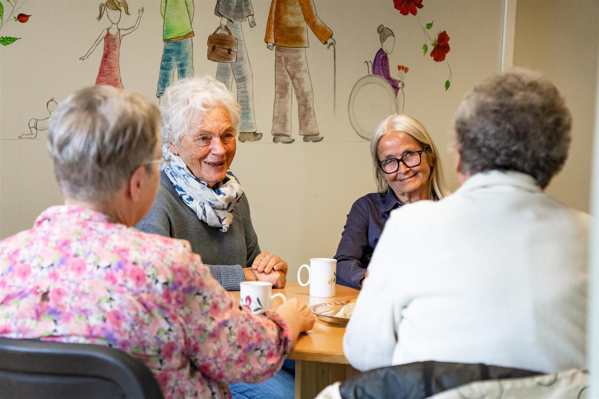 Fire damer som sitter å snakker sammen